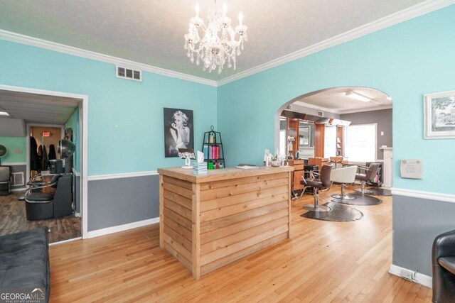 interior space with ornamental molding, a notable chandelier, hardwood / wood-style flooring, and a textured ceiling