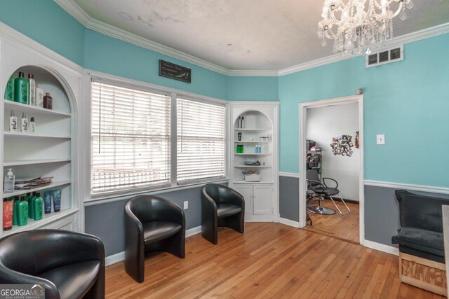 sitting room with ornamental molding, a notable chandelier, and light hardwood / wood-style floors