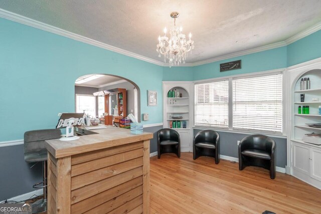 living area featuring a textured ceiling, light wood-type flooring, crown molding, and a notable chandelier