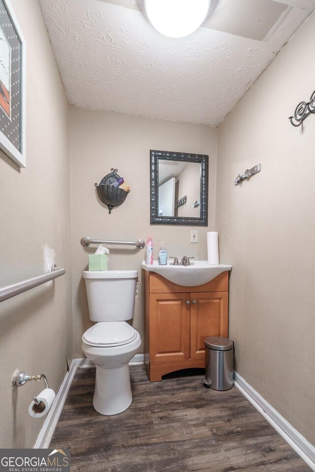 bathroom with vanity, a textured ceiling, hardwood / wood-style flooring, and toilet