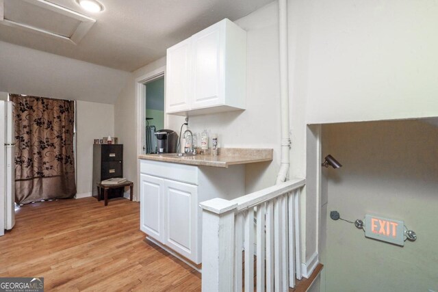 kitchen with light hardwood / wood-style floors, white cabinetry, and sink