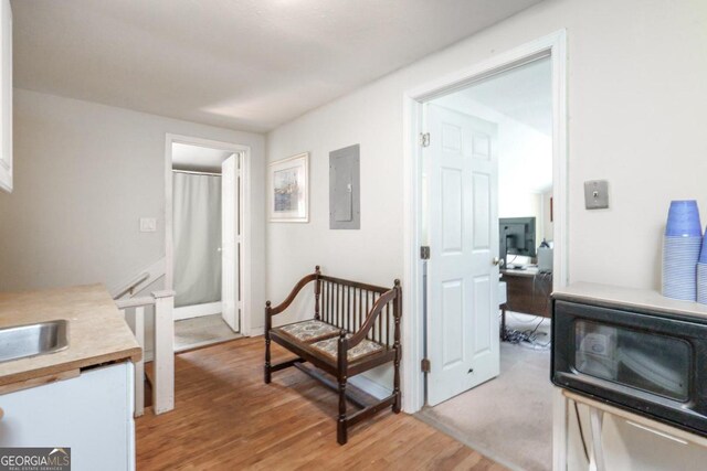 hallway with electric panel and light hardwood / wood-style floors