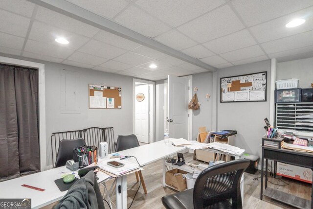 home office with light hardwood / wood-style flooring and a drop ceiling