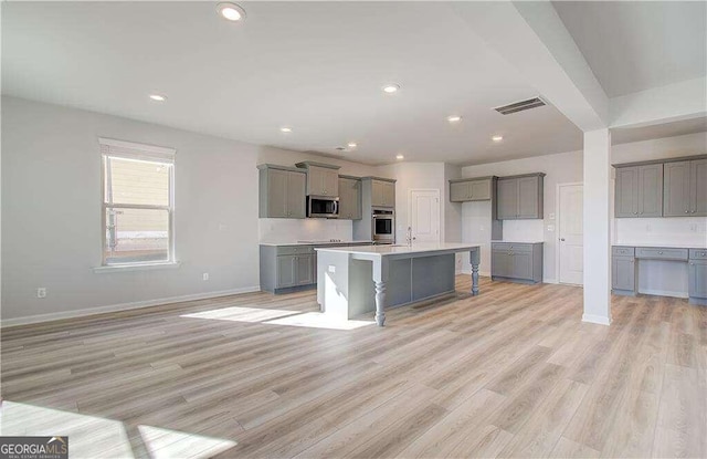 kitchen featuring a center island, stainless steel appliances, light hardwood / wood-style flooring, and gray cabinetry