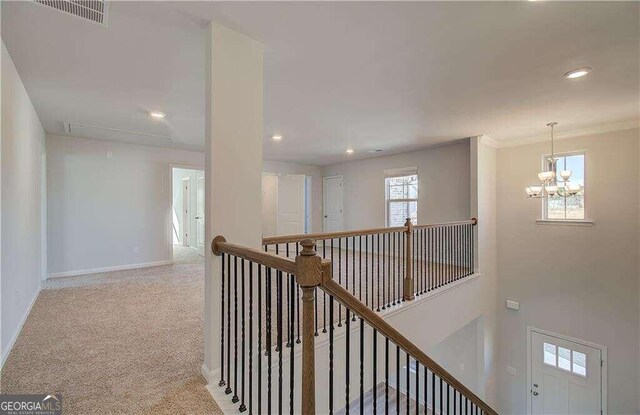 hallway featuring light colored carpet, an inviting chandelier, and crown molding