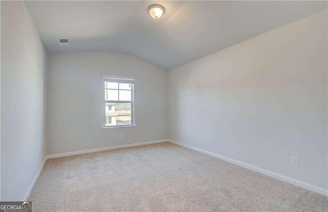 carpeted spare room with lofted ceiling