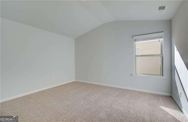 bonus room with vaulted ceiling and light colored carpet