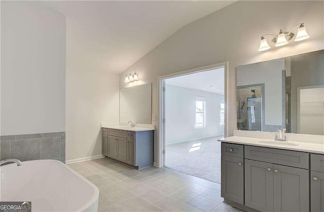 bathroom featuring tile patterned flooring, vanity, a tub to relax in, and vaulted ceiling