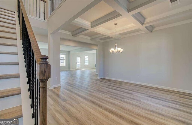 interior space with light hardwood / wood-style flooring, coffered ceiling, beamed ceiling, and an inviting chandelier