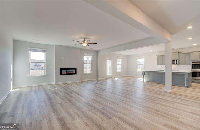 unfurnished living room featuring light hardwood / wood-style flooring and ceiling fan