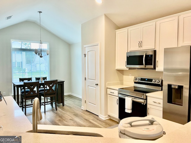 kitchen featuring light wood-type flooring, stainless steel appliances, decorative light fixtures, a notable chandelier, and white cabinets