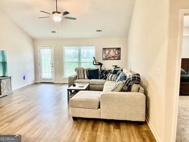 living room with ceiling fan, vaulted ceiling, and light hardwood / wood-style flooring