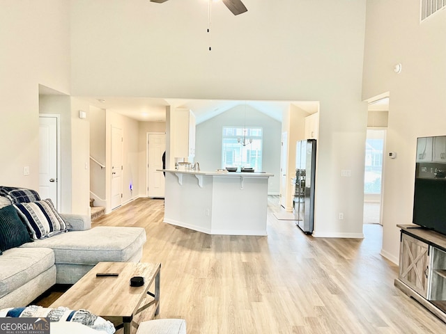 living room featuring light hardwood / wood-style floors, high vaulted ceiling, and ceiling fan