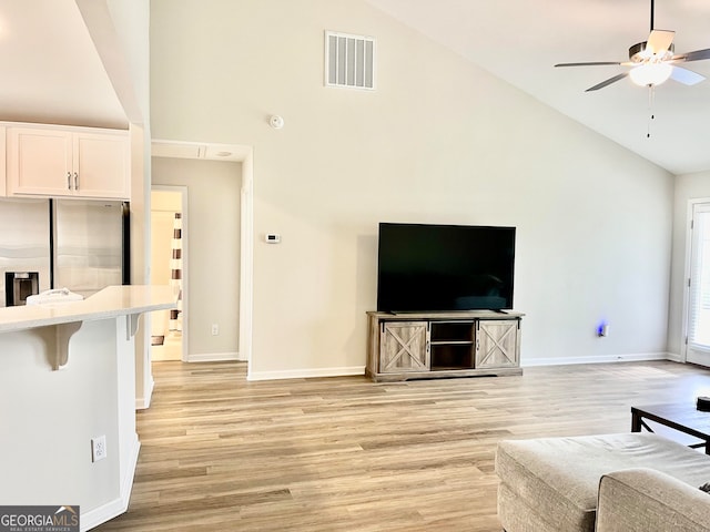 living room featuring ceiling fan, light hardwood / wood-style flooring, and high vaulted ceiling