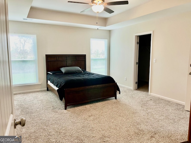 bedroom with light carpet, a spacious closet, multiple windows, and ceiling fan