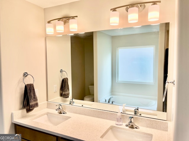 bathroom featuring vanity, a bath, and toilet