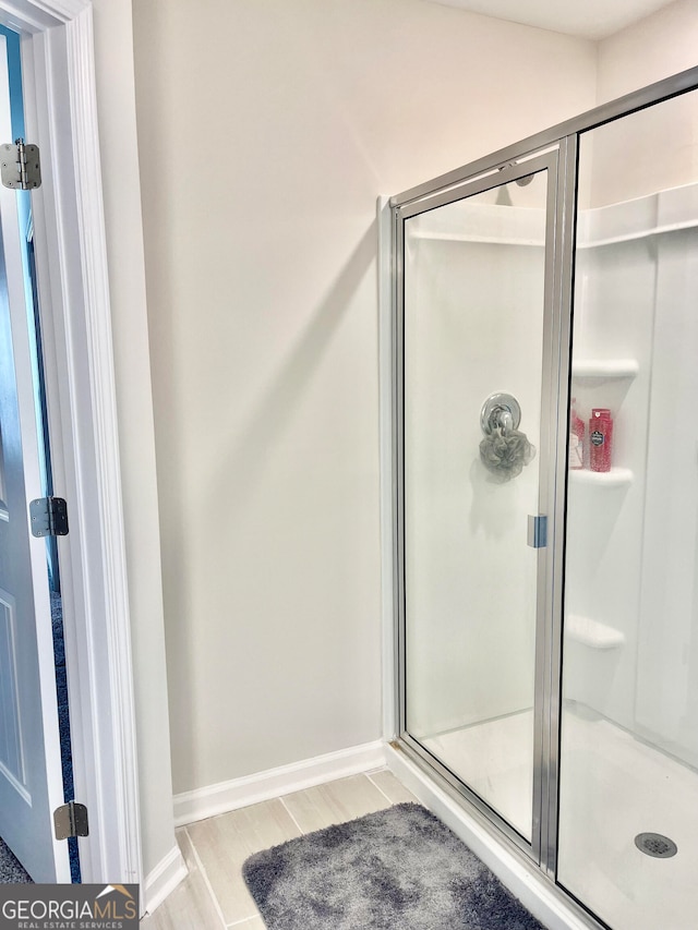 bathroom with an enclosed shower and wood-type flooring