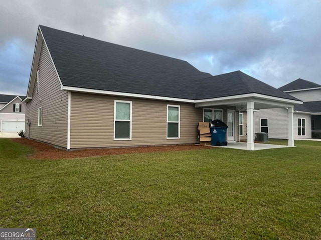 rear view of house with central air condition unit, a patio area, and a lawn