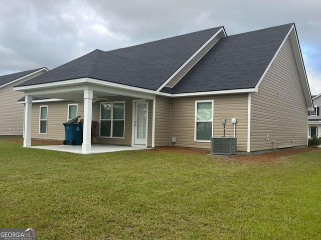 rear view of house with a lawn, central AC, and a patio area