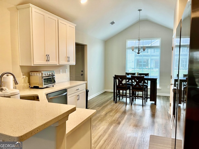 kitchen with white cabinets, decorative light fixtures, vaulted ceiling, and light hardwood / wood-style flooring