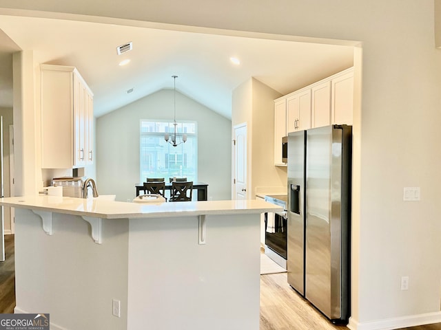 kitchen featuring white cabinets, pendant lighting, stainless steel appliances, and light hardwood / wood-style flooring