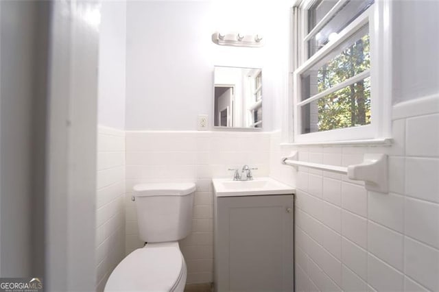 bathroom with vanity, toilet, and tile walls