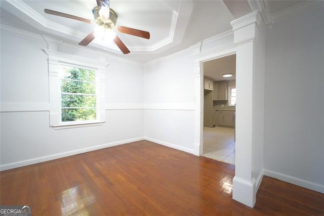 unfurnished room featuring a raised ceiling, ceiling fan, ornamental molding, and light wood-type flooring