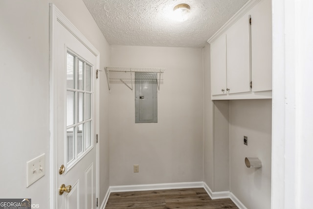 washroom with cabinets, a textured ceiling, electric dryer hookup, dark wood-type flooring, and electric panel