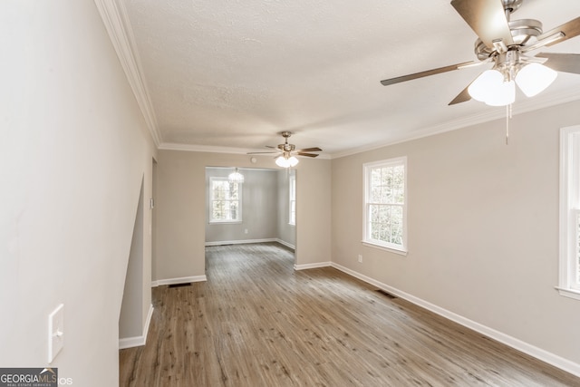 unfurnished room with ceiling fan, crown molding, a healthy amount of sunlight, and light wood-type flooring