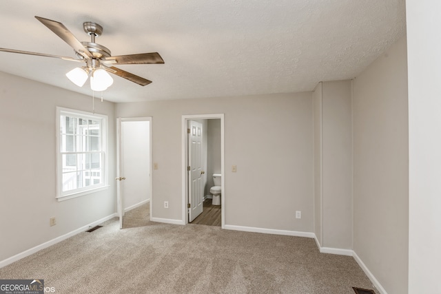 unfurnished bedroom featuring a textured ceiling, ceiling fan, ensuite bathroom, and carpet flooring