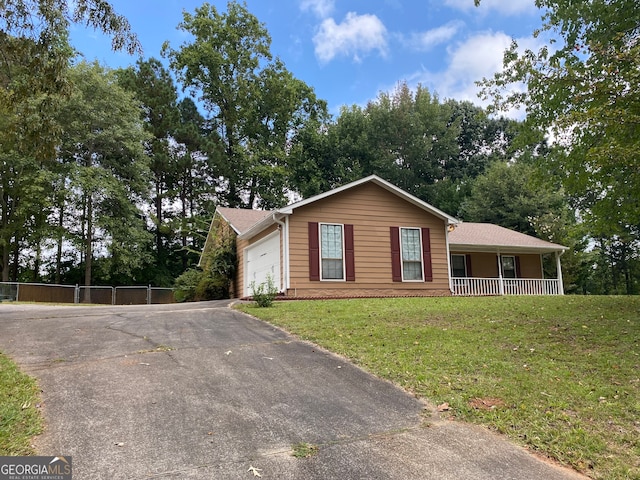 view of front of house featuring covered porch, a front yard, and a garage