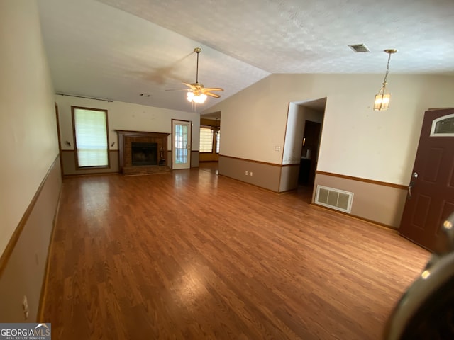 unfurnished living room with ceiling fan, wood-type flooring, a textured ceiling, vaulted ceiling, and a fireplace