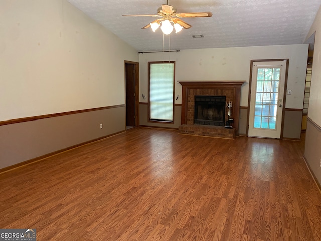 unfurnished living room with ceiling fan, hardwood / wood-style floors, lofted ceiling, a textured ceiling, and a fireplace