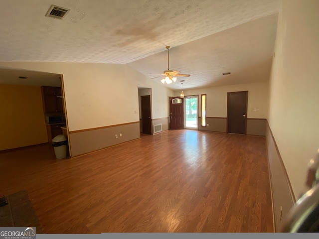 unfurnished room with a textured ceiling, hardwood / wood-style flooring, ceiling fan, and lofted ceiling