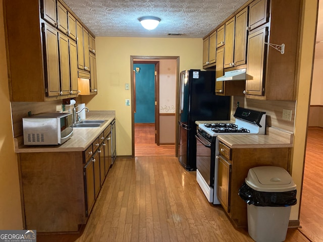 kitchen with light hardwood / wood-style flooring, white range with gas stovetop, a textured ceiling, and sink