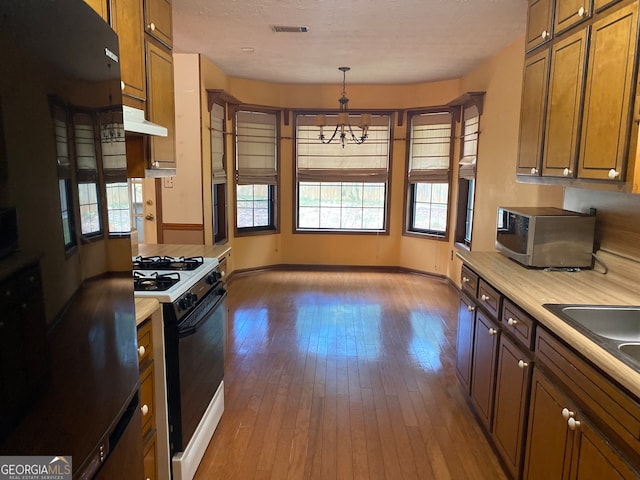 kitchen featuring white gas stove, wood-type flooring, decorative light fixtures, and a notable chandelier