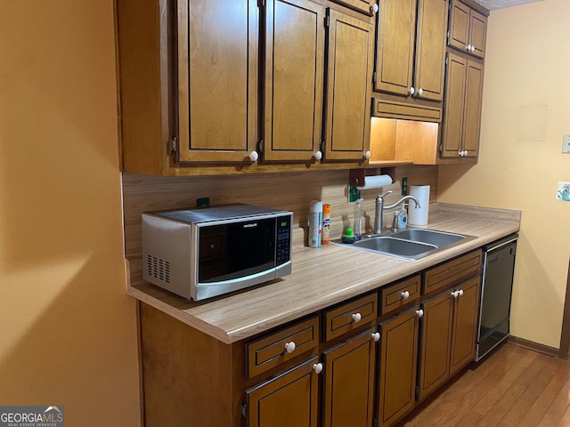 kitchen featuring light wood-type flooring, black dishwasher, backsplash, and sink