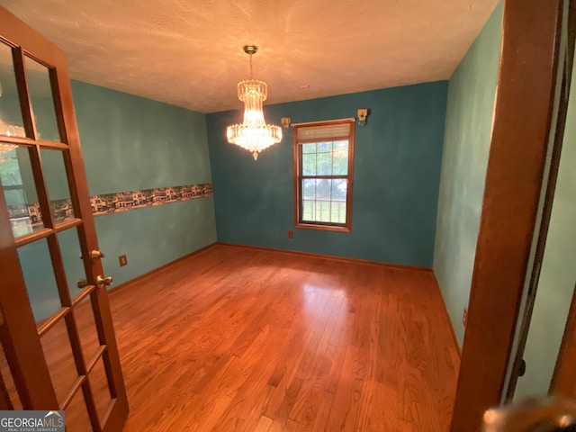 empty room featuring a chandelier and hardwood / wood-style flooring