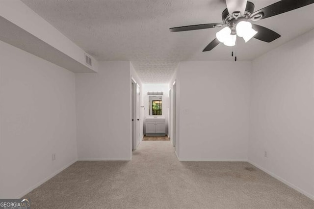 unfurnished room with ceiling fan, light carpet, and a textured ceiling