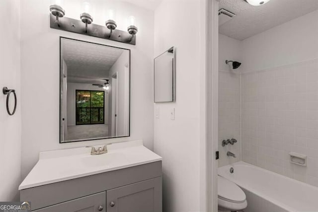 full bathroom with vanity, toilet, tiled shower / bath combo, and a textured ceiling