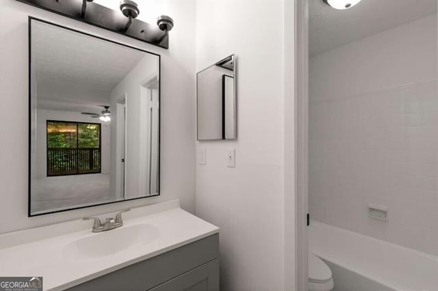 full bathroom featuring bathtub / shower combination, vanity, a textured ceiling, ceiling fan, and toilet