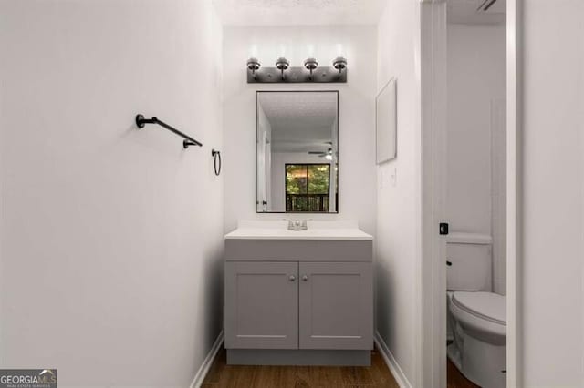 bathroom featuring vanity, toilet, wood-type flooring, and a textured ceiling