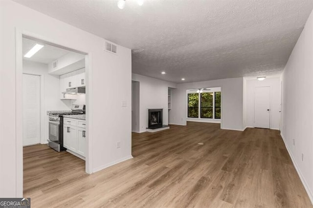 unfurnished living room featuring a textured ceiling, light hardwood / wood-style floors, and ceiling fan