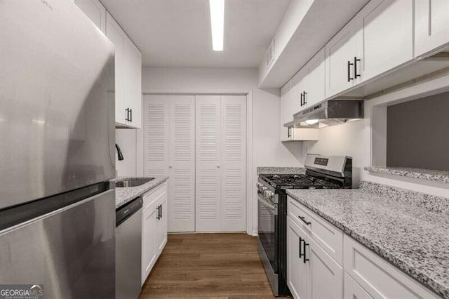 kitchen with white cabinets, sink, dark hardwood / wood-style floors, light stone countertops, and stainless steel appliances