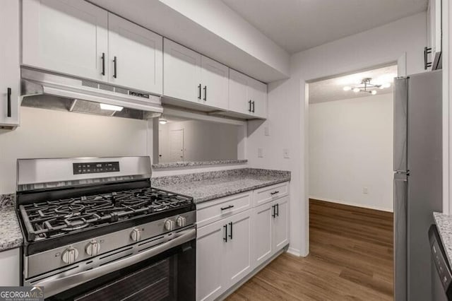 kitchen with light stone countertops, stainless steel appliances, white cabinetry, and hardwood / wood-style flooring