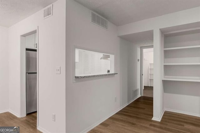 hallway with a textured ceiling and dark hardwood / wood-style flooring