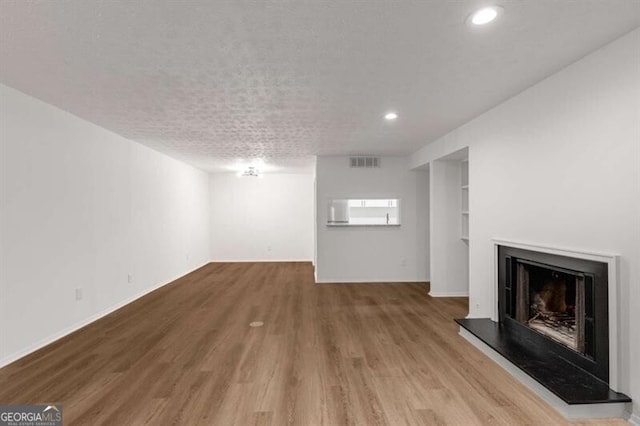 unfurnished living room featuring a textured ceiling and hardwood / wood-style flooring