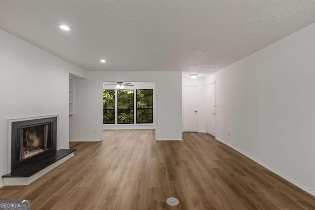 unfurnished living room with a textured ceiling, ceiling fan, and dark wood-type flooring