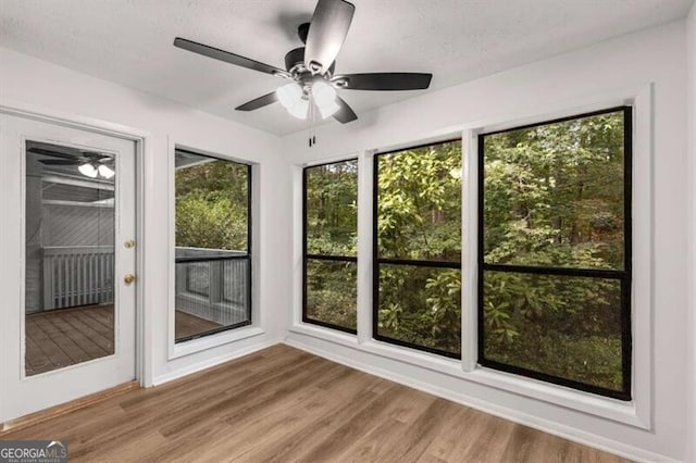 unfurnished sunroom featuring ceiling fan and plenty of natural light