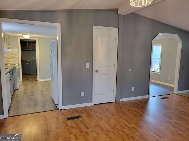 interior space featuring light hardwood / wood-style floors, vaulted ceiling, and white fridge